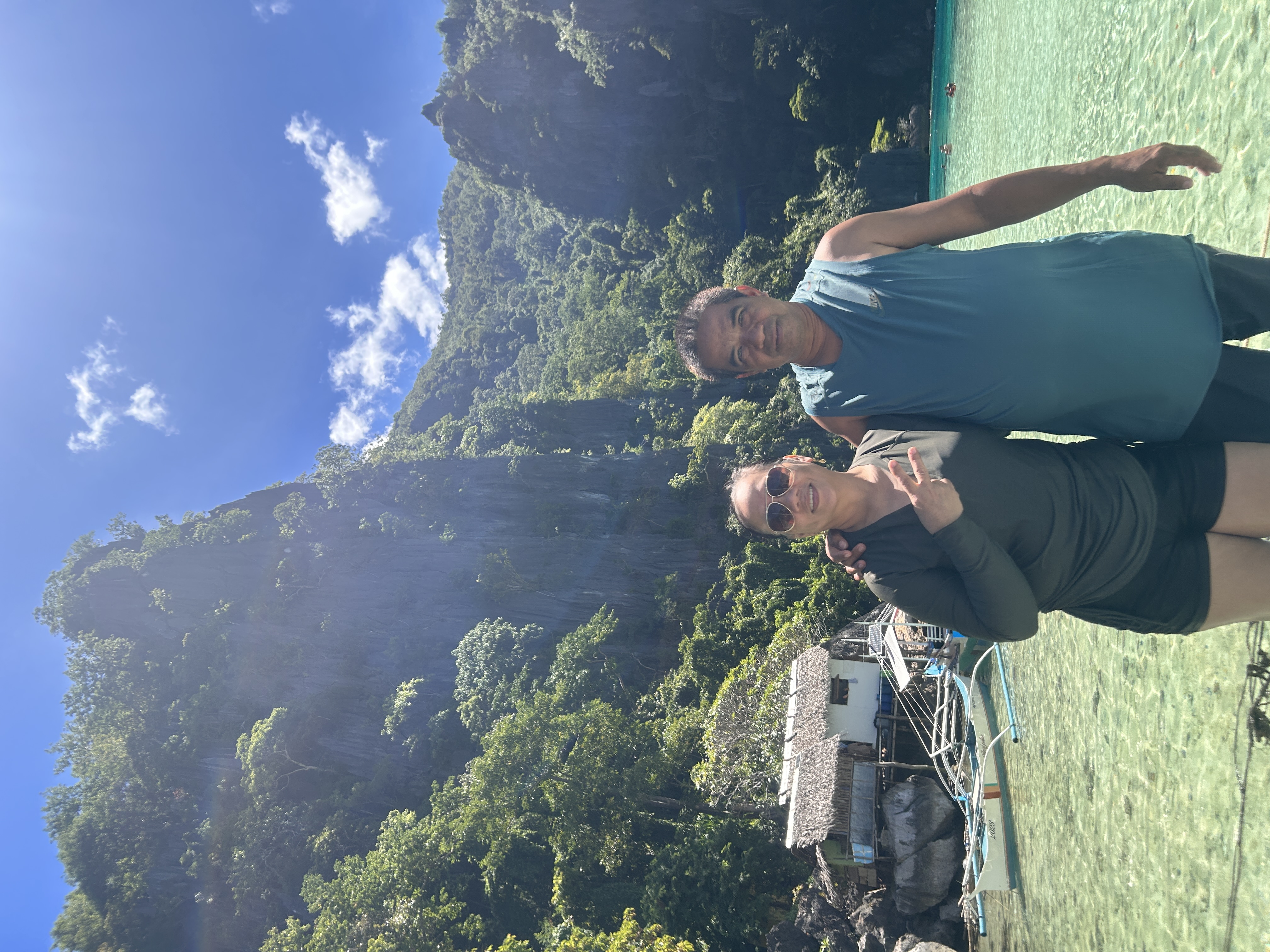 Couple at Twin Lagoon, Coron — crystal-clear water, bangka boat and limestone karsts behind